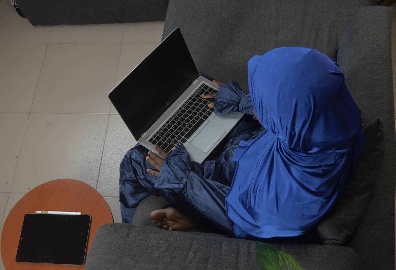A woman in a hijab working on her laptop, seen from above