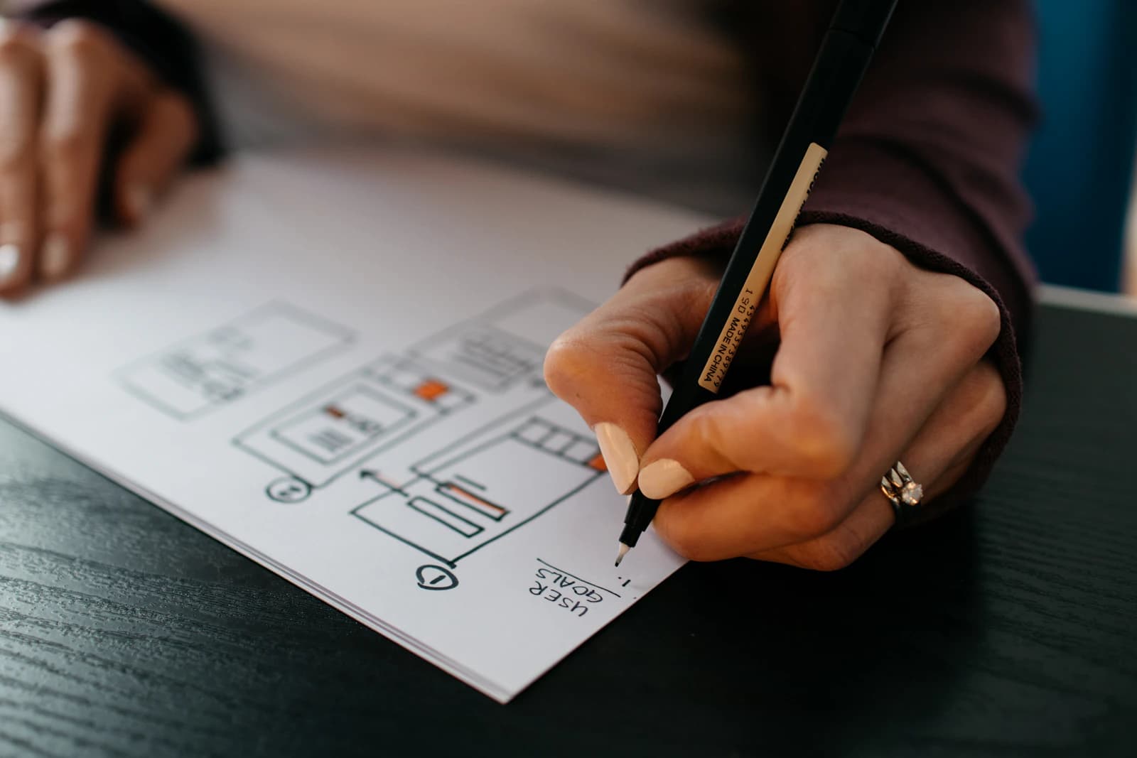 A hand sketching a website wireframe on paper