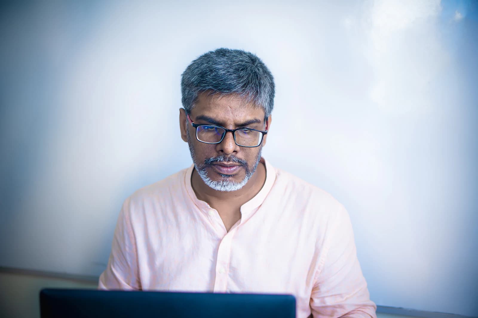 A business owner in glasses working on his laptop