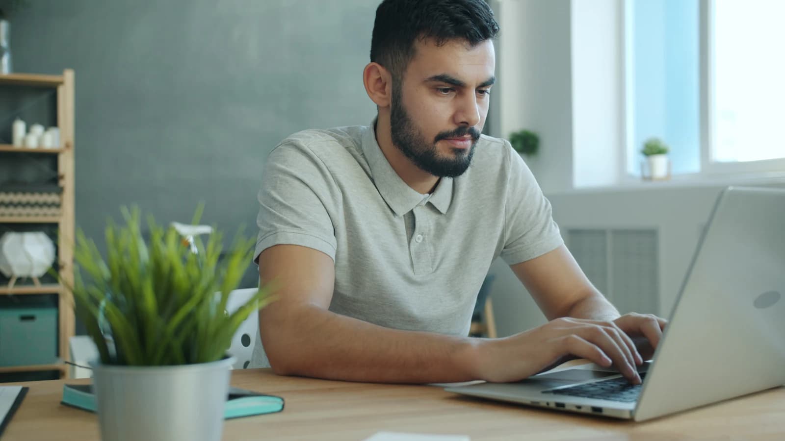 A man typing on his laptop at a light office desk