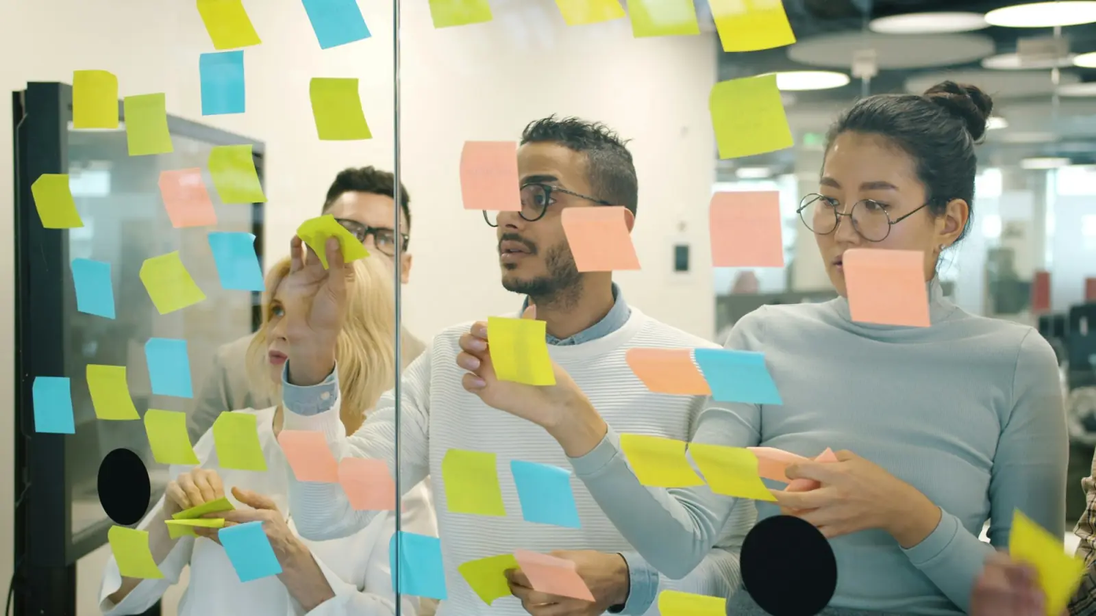 A team planning content together on a glass wall covered in colourful sticky notes