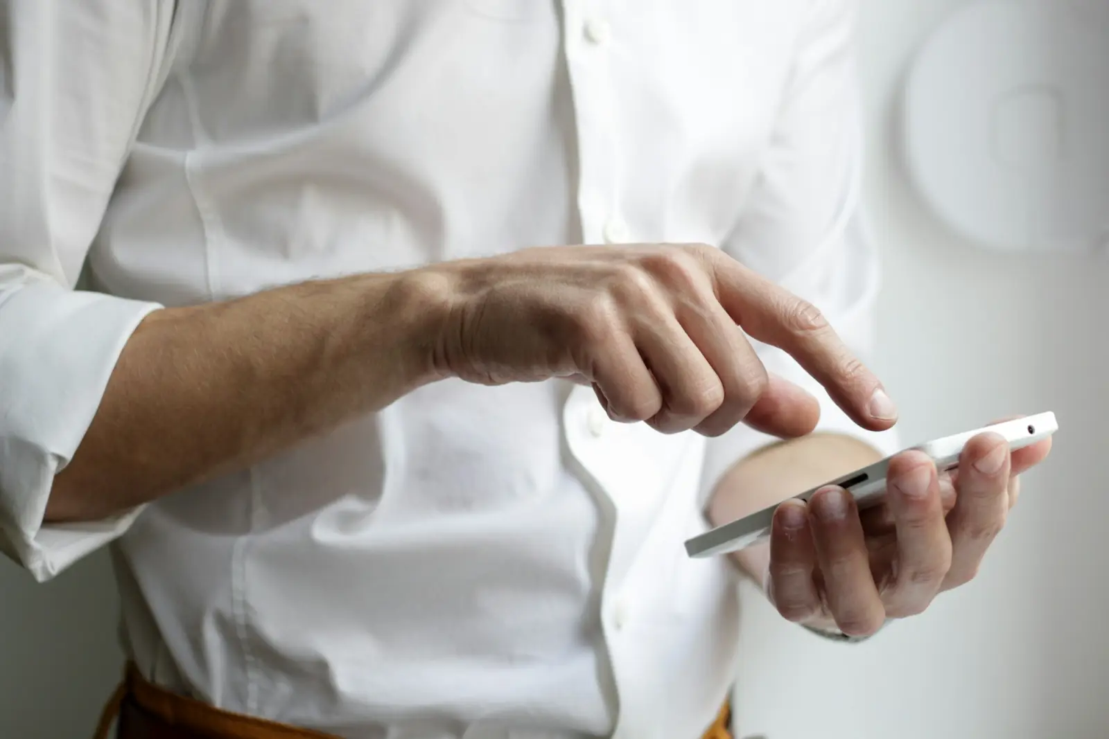 A finger tapping the screen of a phone held in one hand