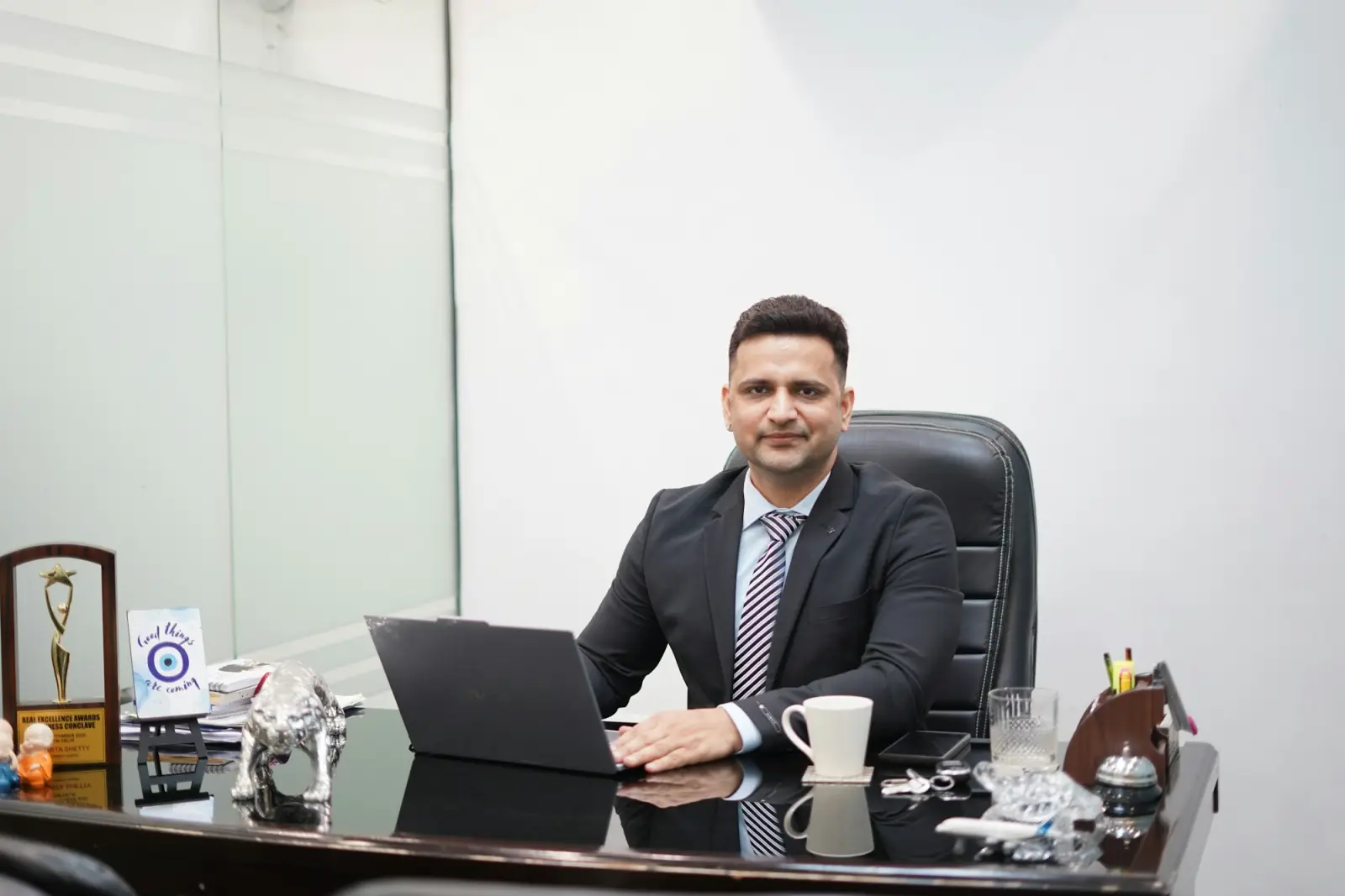 A business owner in a suit at his office desk with his laptop