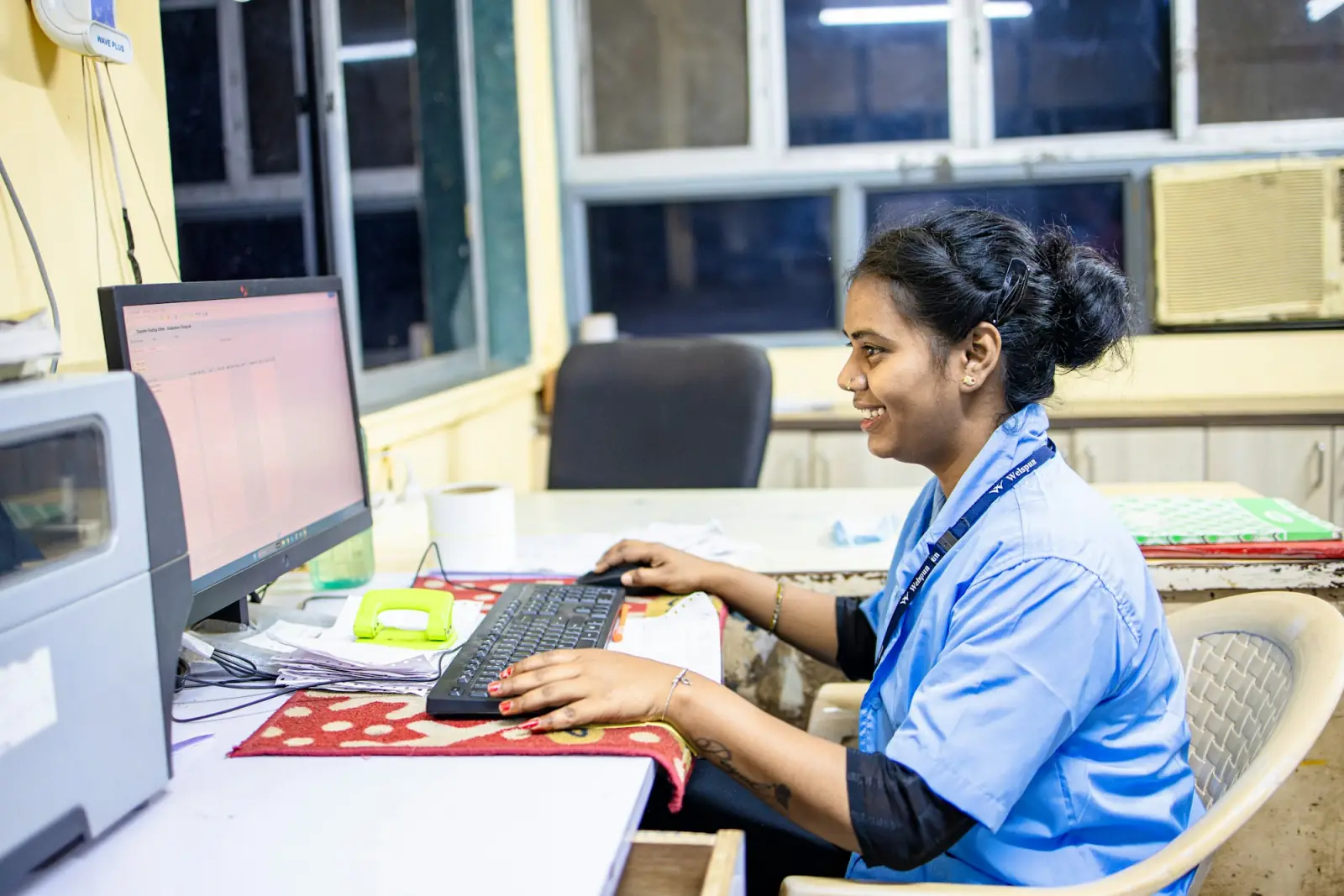 A receptionist at a clinic front desk typing at her computer