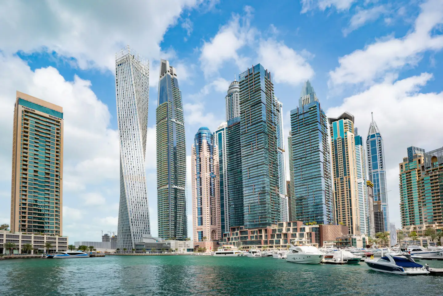 Dubai Marina towers above the water on a bright day, with yachts moored along the quay