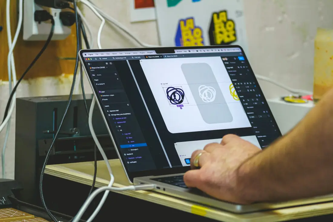 A designer working on a logo on a laptop screen