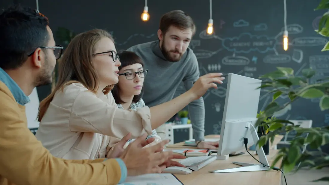 A team gathered around a computer screen, discussing what it shows