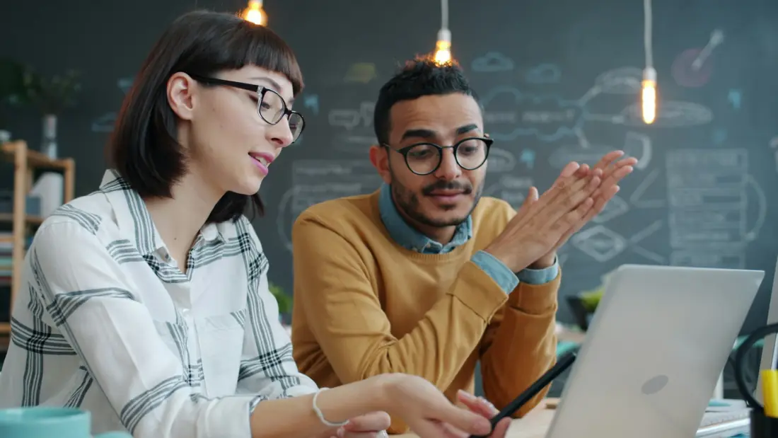 Two colleagues talking through a project at a laptop